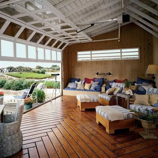 rolled up garage doors open up a countryside living room to the outdoor spaces and make it filled with fresh air and provide cool views