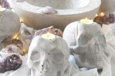 stylish concrete skull candleholders paired with geodes are gorgeous for modern Halloween decor and you cna DIY them