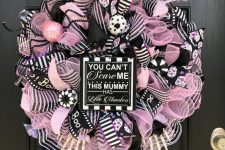07 a fun black, pink and white Halloween wreath with lots of mesh ribbons and striped ones, ornaments, donuts and a sign