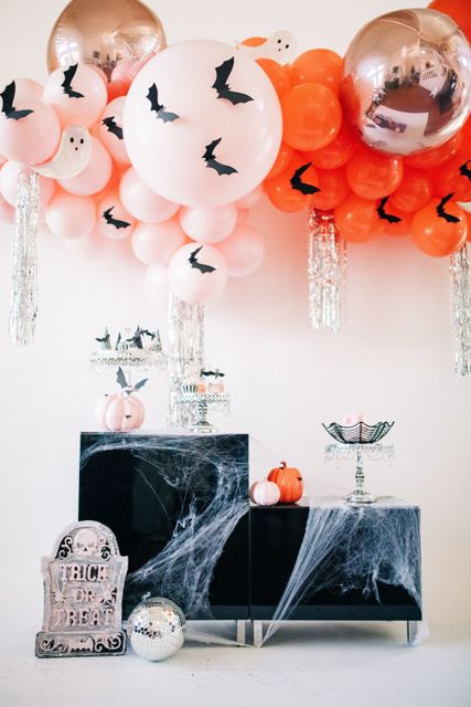 gorgeous Halloween decor with pink and orange balloons and bats, with storage furniture covered with spiderweb, bats and disco balls