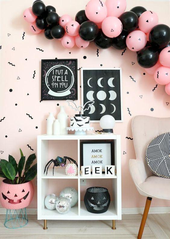 fab Halloween decor in pink and black, with a balloon garland and some artworks, spiders and disco balls is a lovely idea