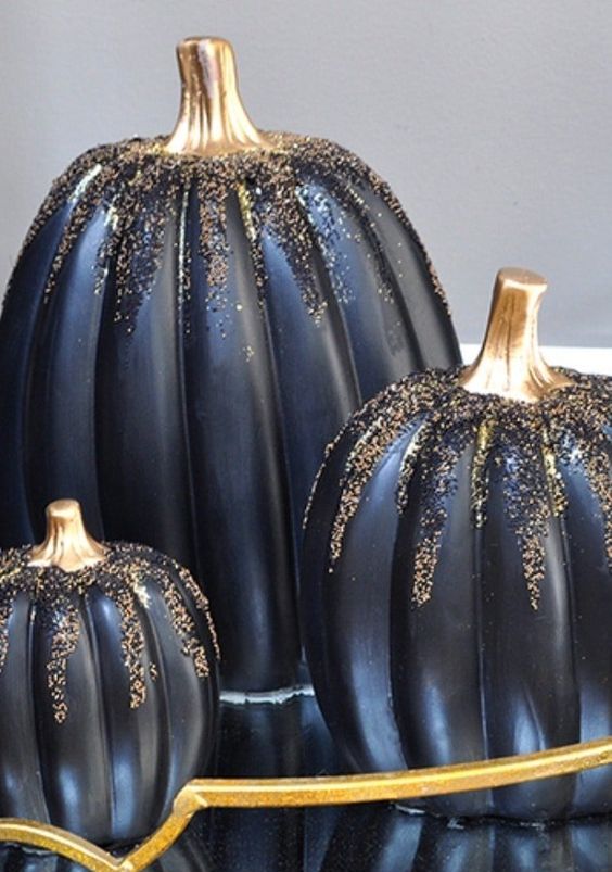 a trio of refined and glam black pumpkins covered with gold and black glitter are amazing for Halloween decor