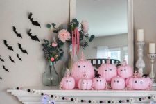 15 a fun Halloween mantel with pink pumpkins with googly eyes and skeletons, bats and a bat and ghost garland