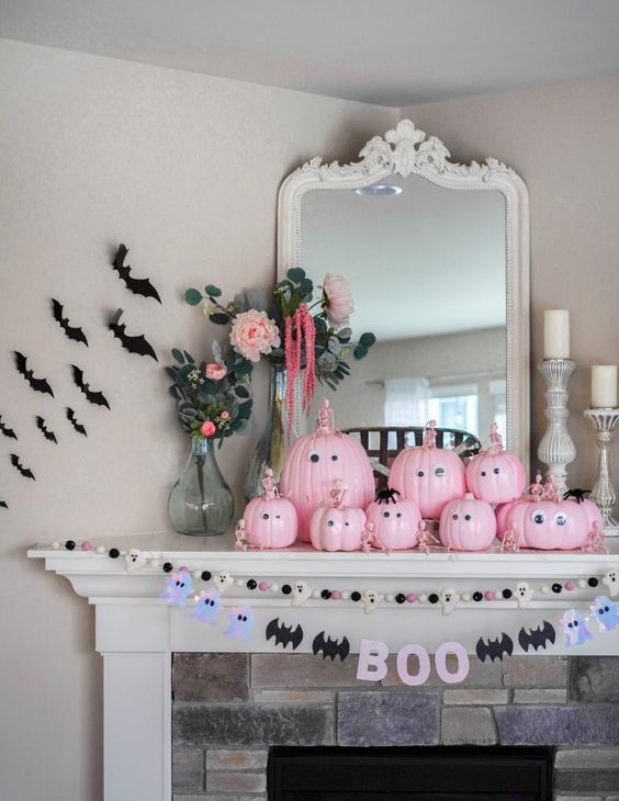 a fun Halloween mantel with pink pumpkins with googly eyes and skeletons, bats and a bat and ghost garland