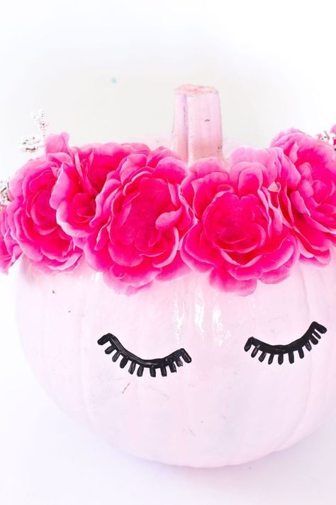 a glossy pink pumpkin with pink flowers and shut eyes is a very cool and bold decoration for Halloween