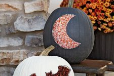 19 a black and white pumpkin decorated with nails and yarn showing a bat and a moon for chic and bold Halloween decor