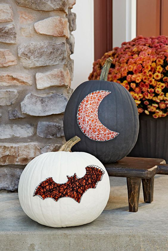 a black and white pumpkin decorated with nails and yarn showing a bat and a moon for chic and bold Halloween decor