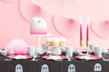 20 a pretty Halloween sweets table in pink and black, with pink paper fans, pink candles and a cake, pink ghost plates and a ghost tablecloth