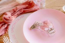21 a pretty pink Halloween tablescape with a blush runner and a coral napkin, a pink plate and a skull and a skeleton hand is amazing