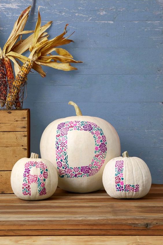 white pumpkins with pink floral monograms painted are a non-typical and very cute Halloween decor idea