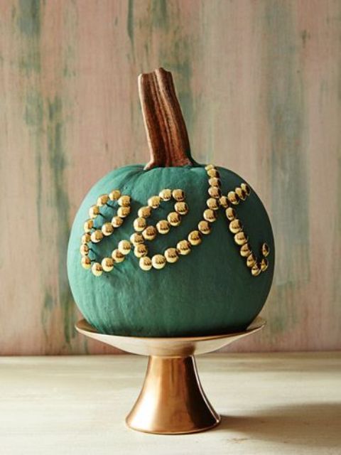 a chic matte green pumpkin decorated with gold beads is a chic and stylish decoration for Halloween