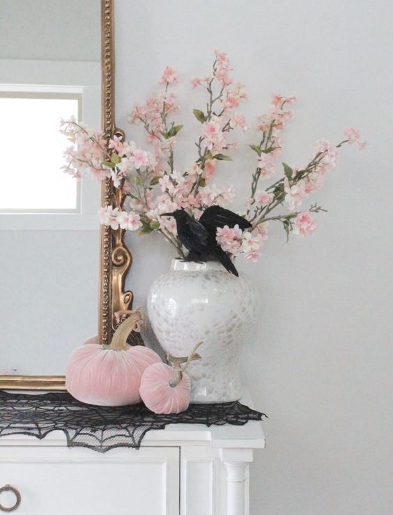 glam Halloween decor with faux pink blooms and pink velvet pumpkins plus a black lace spiderweb on the mantel is all cool