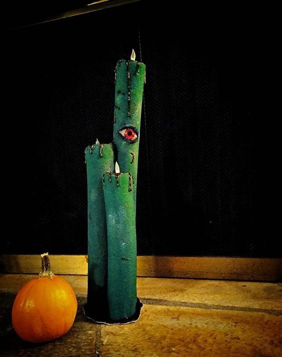 a scary Halloween decoration of green pool noodles turned into candles with blood and eyes is a gorgeous and easy DIY idea