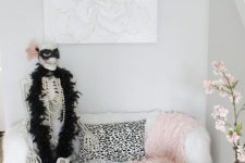26 glam Halloween decor with pink and black velvet pumpkins, a pink lace blanket and a skeleton dressed up in a chic way