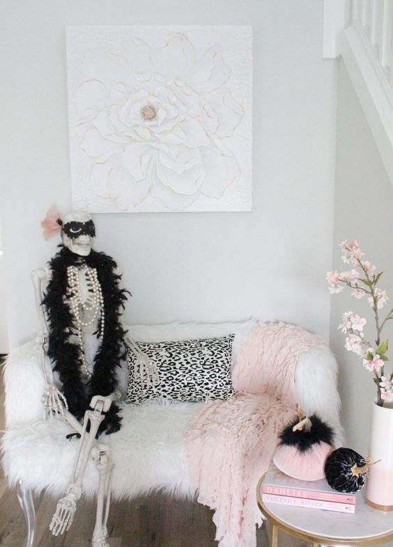glam Halloween decor with pink and black velvet pumpkins, a pink lace blanket and a skeleton dressed up in a chic way