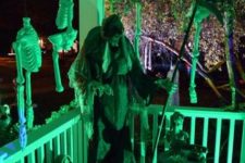 27 a scary Halloween scene on the porch, with death, skulls and skeleton parts, chains lit up in green for a spookier look