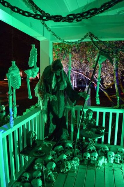 a scary Halloween scene on the porch, with death, skulls and skeleton parts, chains lit up in green for a spookier look