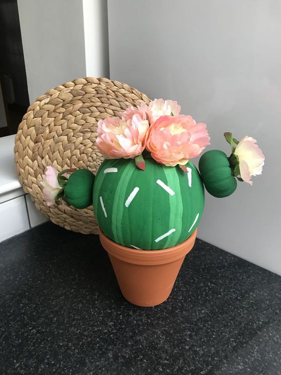 a pumpkin turned into a fun and colorful cactus, topped with paper blooms is a gorgeous idea for Halloween