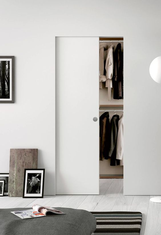 a Scandinavian bedroom with a smartly hidden wardrobe with a sleek pocket door is a very cool idea to integrate your closet in a smart way