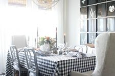 a Thanksgiving tablescape with a buffalo check tablecloth, grey napkins, black candles, a floral centerpiece and greenery