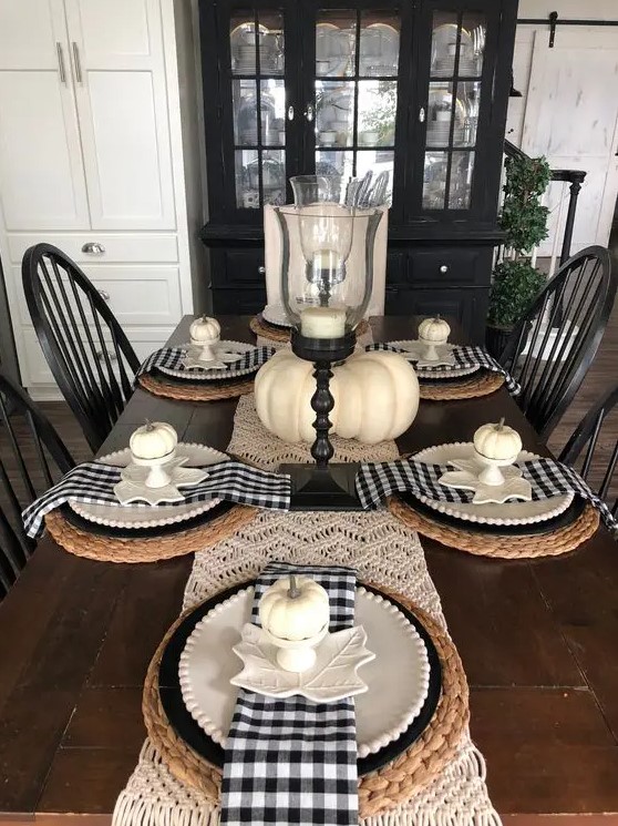 a Thanksgiving tablescape with a macrame runner, woven placemats, buffalo check napkins, white pumpkins and elegant candleholders