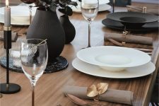 a chic black and white Thanksgiving tablescape with black and white porcelain, brass cutlery, black candleholders and vases