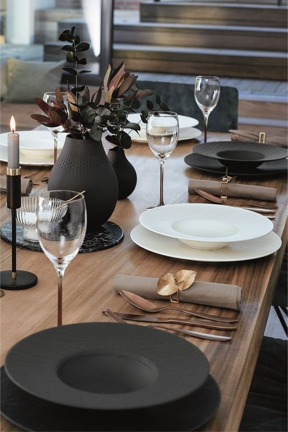 a chic black and white Thanksgiving tablescape with black and white porcelain, brass cutlery, black candleholders and vases