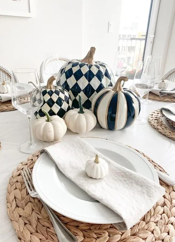 a chic modern farmhouse Thanksgiving tablescape with black and white pumpkins, woven placemats, neutral linens and glasses