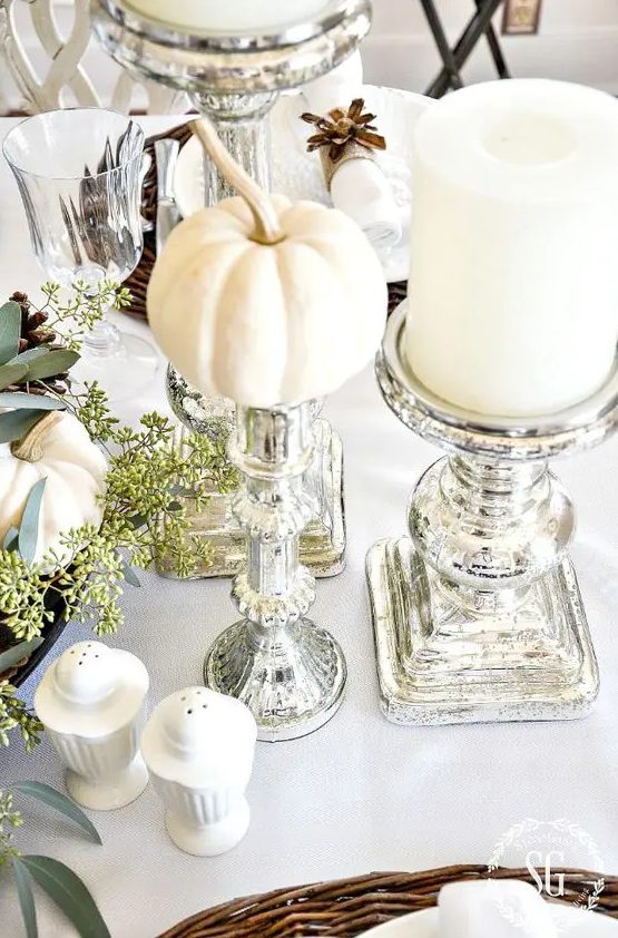 a chic neutral Thanksgiving tablescape with mini pumpkins, large candles, mercury glass candleholders and some greenery