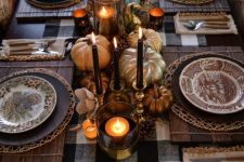 a chic traditional Thanksgiving tablescape with a buffalo check tablecloth, wooden placemats, black candles, metallic pumpkins, candles and patterned plates