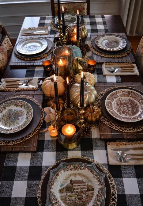 a chic traditional Thanksgiving tablescape with a buffalo check tablecloth, wooden placemats, black candles, metallic pumpkins, candles and patterned plates