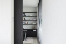 a contemporary space with black accents and a black double-height pocket door that is another color accent in the space