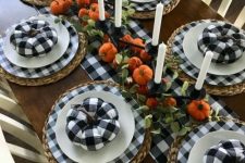 a cool Thanksgiving tablescape with buffalo check linens, plates and pumpkins, bright orange fabric pumpkins and tall and thin candles