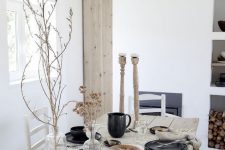 a cozy  and simple black and white Thanksgiving tablescape with black porcelain, white linens, dried grasses and branches