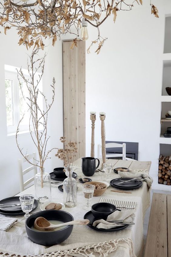 a cozy  and simple black and white Thanksgiving tablescape with black porcelain, white linens, dried grasses and branches