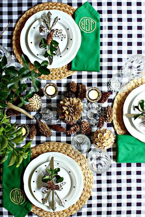 a fab modern Thanksgiving tablescape with a buffalo check tablecloth, woven chargers, bright green napkins, greenery and pinecones