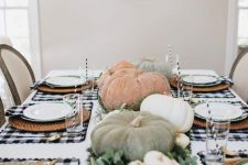 a farmhouse Thanksgiving tablescape with buffalo check placemats, natural pumpkins and greenery, woven placemats