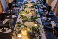 a glam black and white Thanksgiving tablescape with a white runner, black glasses, black and white pumpkins, black plates and white blooms