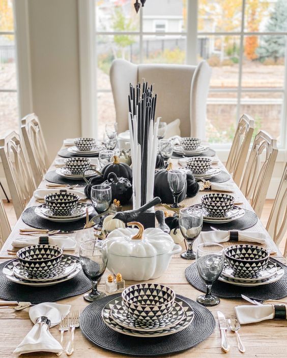 a modern Thanksgiving table setting with geo print tableware, black and white candles, pumpkins and grey glasses