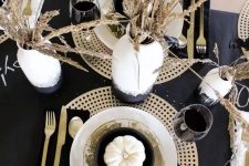 a modern and exquisite Thanksgiving tablescape with gold chargers and cutlery, black linens and wheat in black and white vases