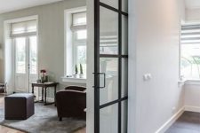 a modern black and white space with elegant black metal French doors that are pocket ones is filled with light and air