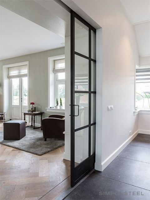 a modern black and white space with elegant black metal French doors that are pocket ones is filled with light and air