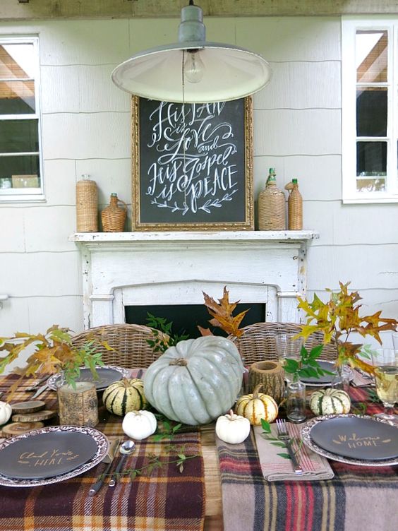 a modern farmhouse Thanksgiving tablescape with mismatching plaid tablecloths and napkins, natural pumpkins and fall leaves