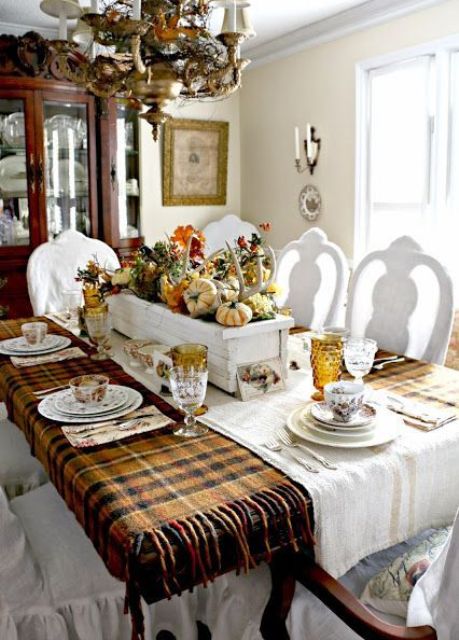 a natural Thanksgiving tablescape with a plaid tablecloth, a box with antlers, gourds and leaves and colored copper glasses