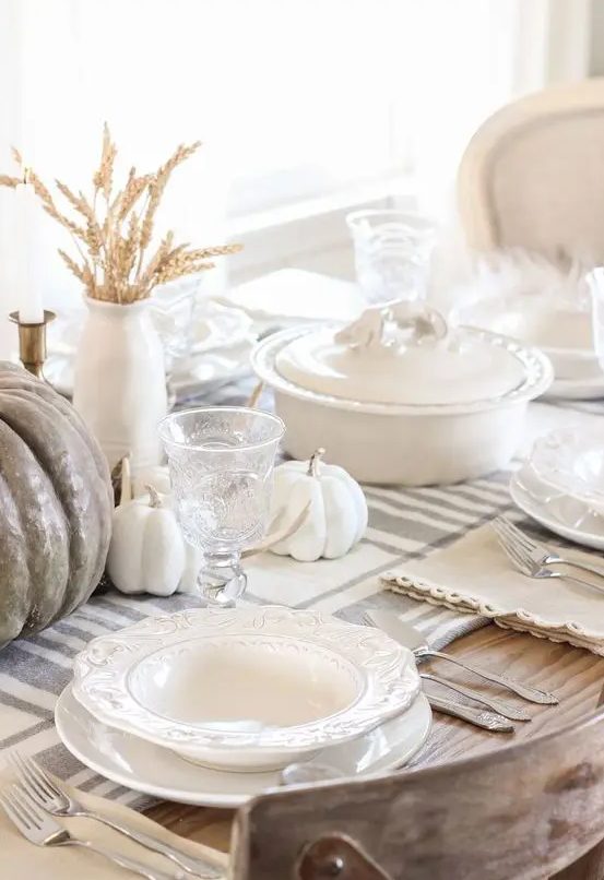 a neutral rustic Thanksgiving tablescape with a striped runner, white and taupe pumpkins, wheat and white porcelain