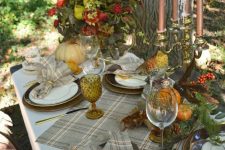 a refined vintage forest Thanksgiving tablescape with plaid linens, various porcelain, copper candles, feathers, bold blooms, pinecones and feathers