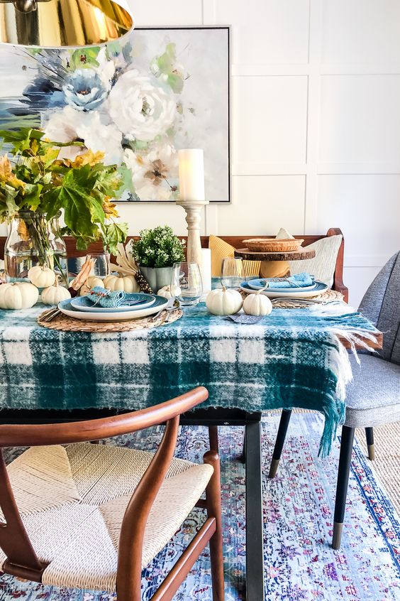a rustic bright Thanksgiving tablescape with a blue plaid tablecloth and blue plates, fresh leaves and gourds for a centerpiece