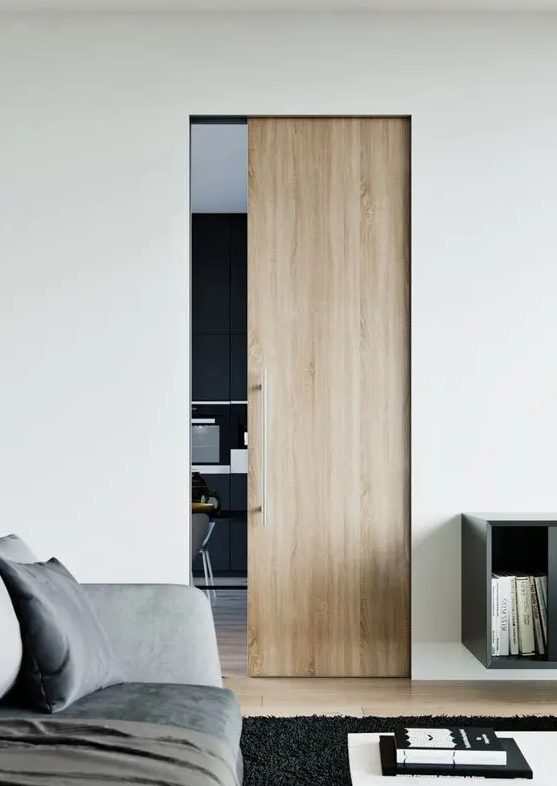 a small light stained pocket door with sleek and long handle is a stylish way to separate the spaces in a contemporary home