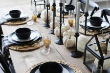 a stylish farmhouse Thanksgiving tablescape with woven placemats, black and white black and black bowls, black candleholders and white pumpkins