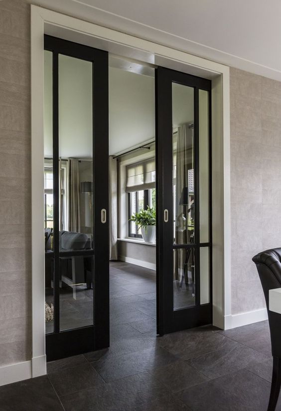 a stylish modern space with tan walls and dark tiles on the floor plus black glass pocket doors for a chic statement and a slight touch of color